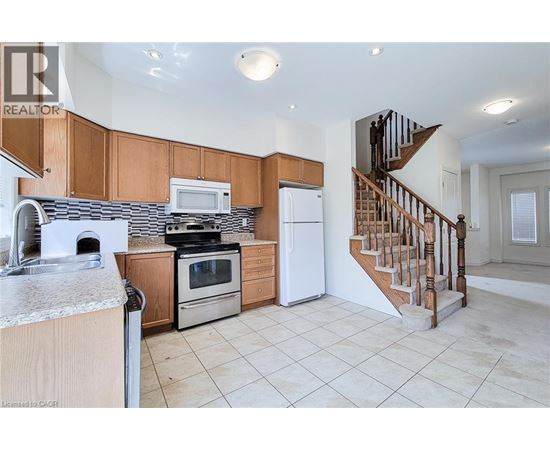 A kitchen with wooden cabinets and a staircase.