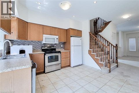 A kitchen with wooden cabinets and a staircase.