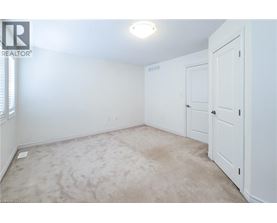 A white bedroom with a carpeted floor and a single light fixture on the ceiling.