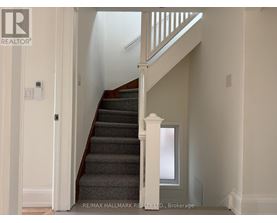 A staircase with a white railing and a grey carpet.