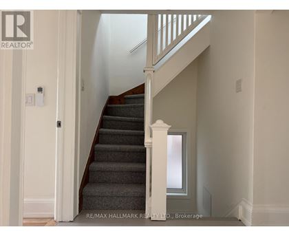 A staircase with a white railing and a grey carpet.