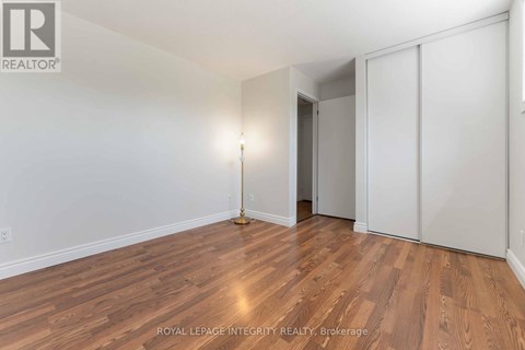 A room with wooden flooring and a single lamp on the floor.