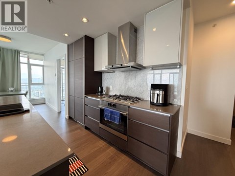 A modern kitchen with dark wood cabinets and stainless steel appliances.