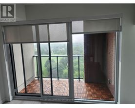 A balcony with a glass door leading to a view of trees.
