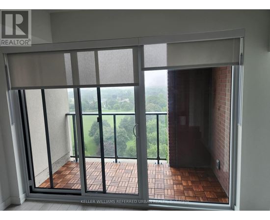 A balcony with a glass door leading to a view of trees.