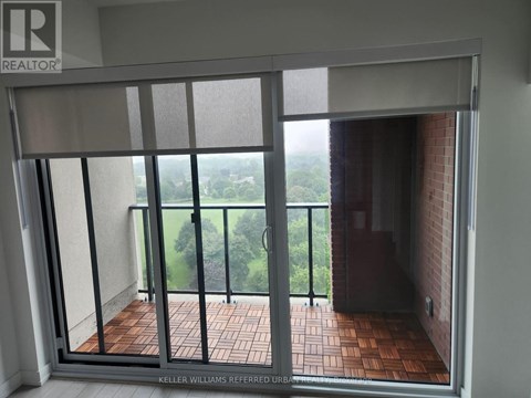 A balcony with a glass door leading to a view of trees.
