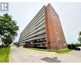 A tall apartment building with a parking lot in front.