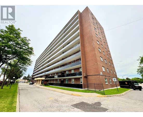 A tall apartment building with a parking lot in front.