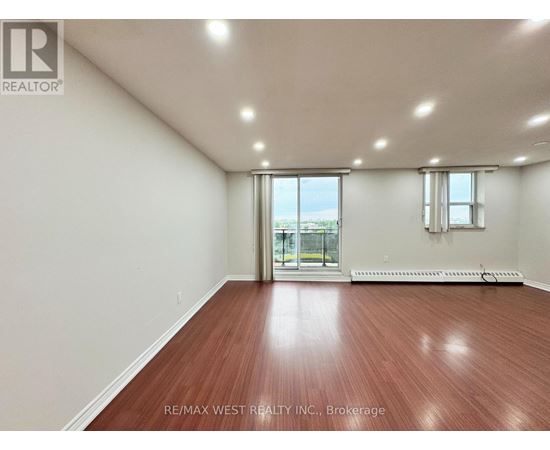 A room with a wooden floor and a sliding glass door leading to a balcony.