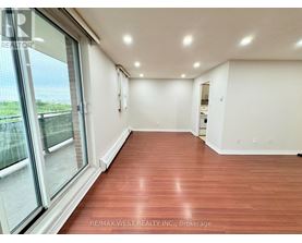A spacious room with wood flooring and large windows.