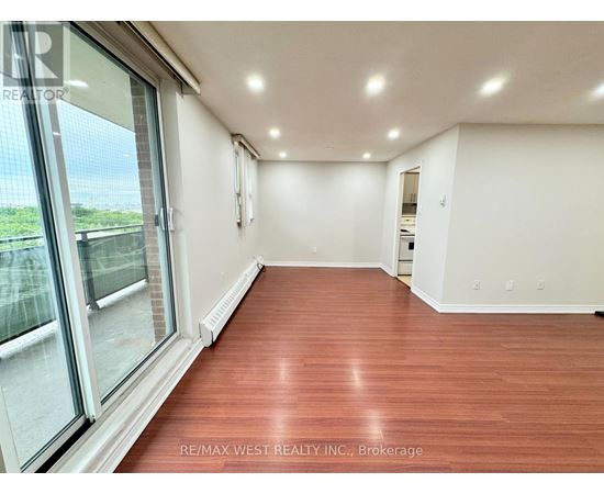A spacious room with wood flooring and large windows.
