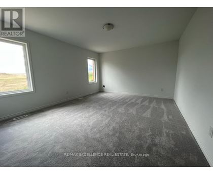 A room with a grey carpet and two windows.