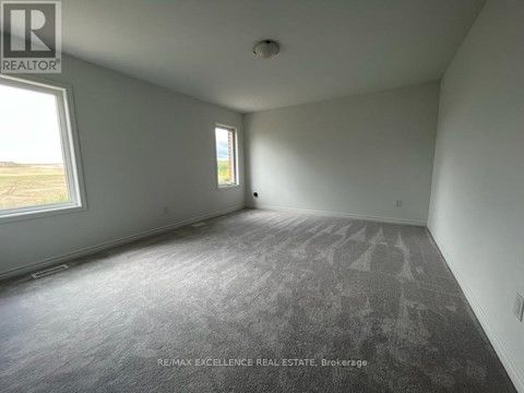 A room with a grey carpet and two windows.