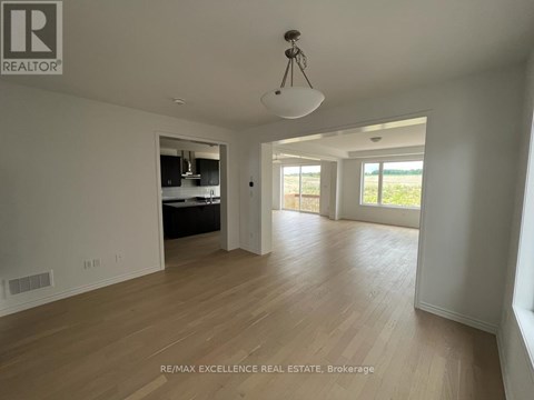 A spacious room with wooden flooring and a large window.