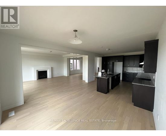 A spacious living room with a fireplace and a kitchen area with black cabinets.