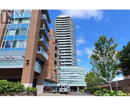 A tall building with a glass facade stands next to a shorter brick building.