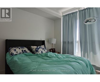A bedroom with a bed, pillows, a nightstand, and a window with curtains.