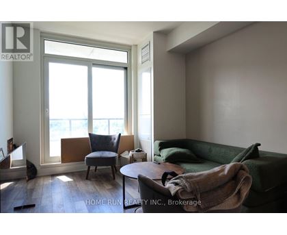 A living room with a green couch and a chair by a window.