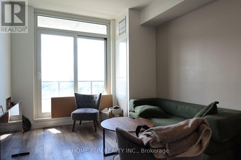 A living room with a green couch and a chair by a window.