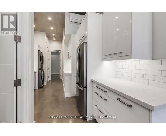 A white kitchen with a re/max west realty logo.