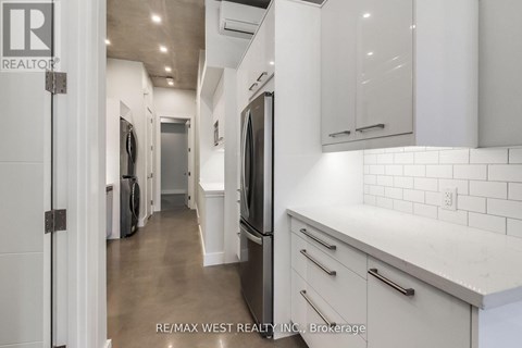 A white kitchen with a re/max west realty logo.