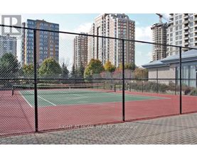 A tennis court is enclosed by a black fence.