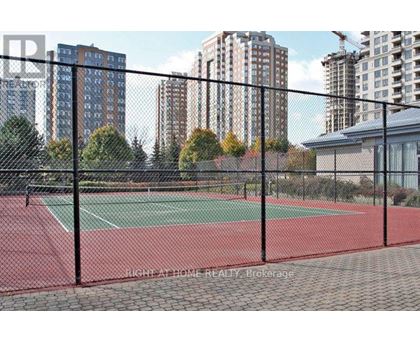A tennis court is enclosed by a black fence.