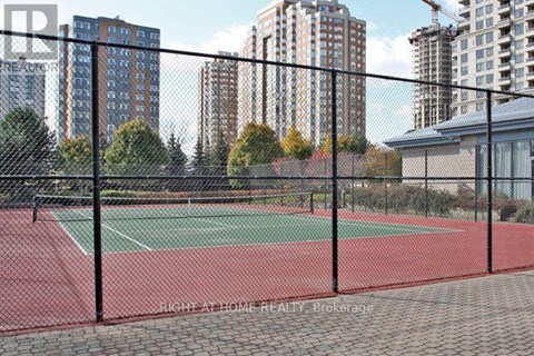 A tennis court is enclosed by a black fence.