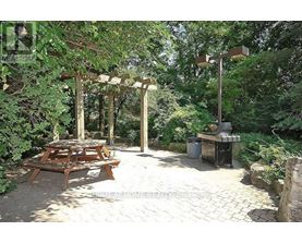 A wooden picnic table is set up under a pergola in a backyard.