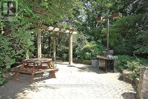 A wooden picnic table is set up under a pergola in a backyard.