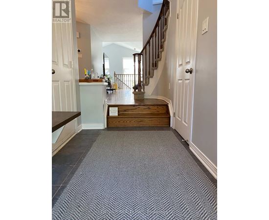 A hallway with a staircase and a carpeted floor.