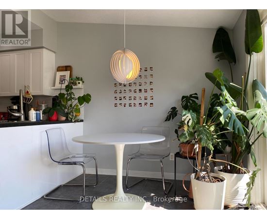 A white table with chairs and a hanging light fixture in a kitchen.