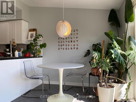 A white table with chairs and a hanging light fixture in a kitchen.