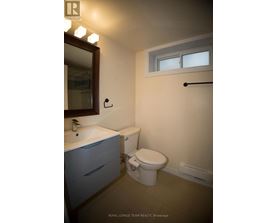A white toilet sits in a bathroom with a sink and mirror.