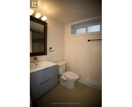 A white toilet sits in a bathroom with a sink and mirror.