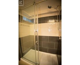 A shower area with a glass door and a black tile wall.