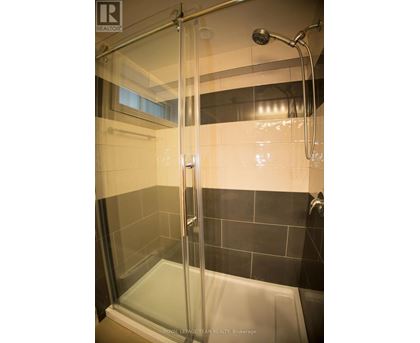 A shower area with a glass door and a black tile wall.