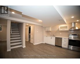 A spacious kitchen with stainless steel appliances and white cabinetry.