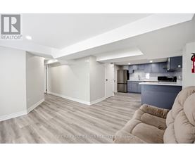 A spacious living room with a grey kitchen in the background.