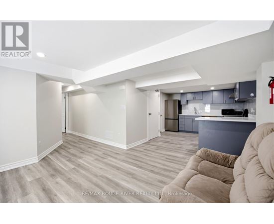 A spacious living room with a grey kitchen in the background.