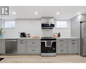 A modern kitchen with a black oven and grey cabinets.