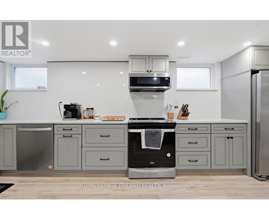 A modern kitchen with a black oven and grey cabinets.