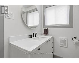 A white bathroom sink with a round mirror above it.