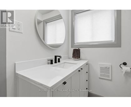 A white bathroom sink with a round mirror above it.