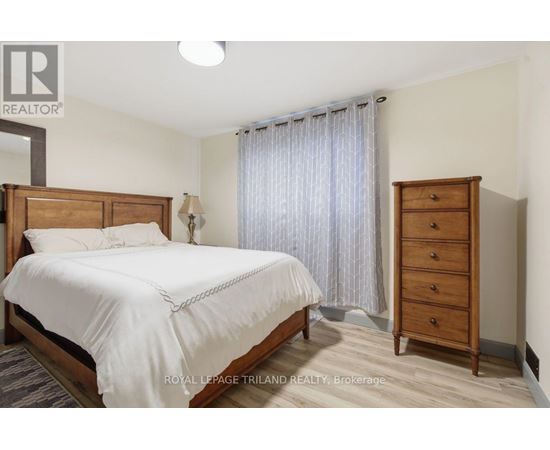 A bedroom with a large bed, a nightstand, and a wooden wardrobe.