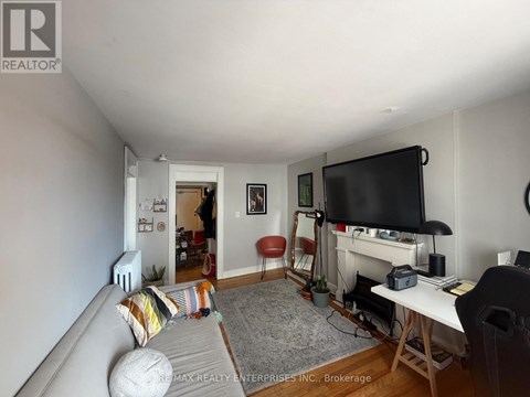 A living room with a grey couch and a television on the wall.