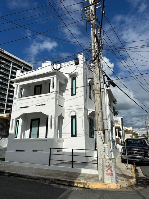 A white building with a black truck parked in front of it.