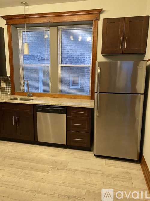 A kitchen with a refrigerator, sink, and window.