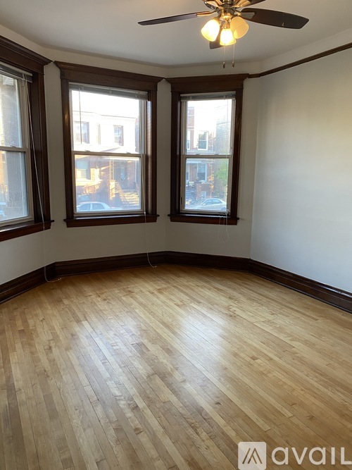 A room with wooden flooring and two windows.