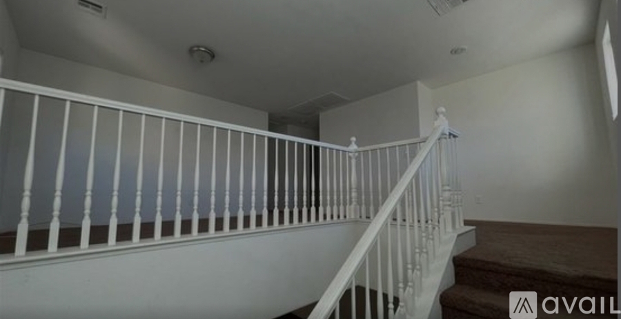 A staircase with white railings and a light brown carpet.